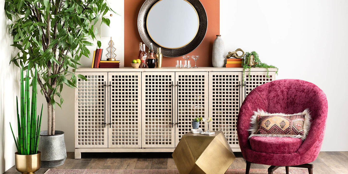 Lots of different colors shown in a room with green plants, tan credenza, pink chair and lots of colorful accents