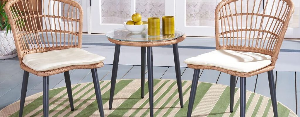 Light tan wicker bistro patio set on backyard porch with coffee table set between two chairs