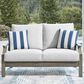 Ashley Rainier Ranch Outdoor Loveseat with Beige Cushion in Brown, , large