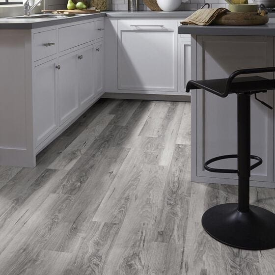 kithchen with white cabinets a black counter stool and light wood color vinyl plank flooring