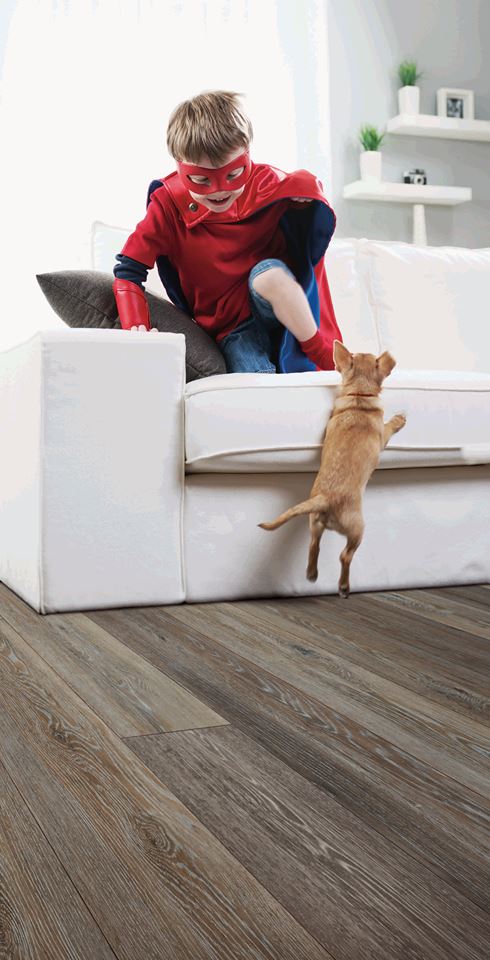 Child in superhero costume playing with dog in home living room